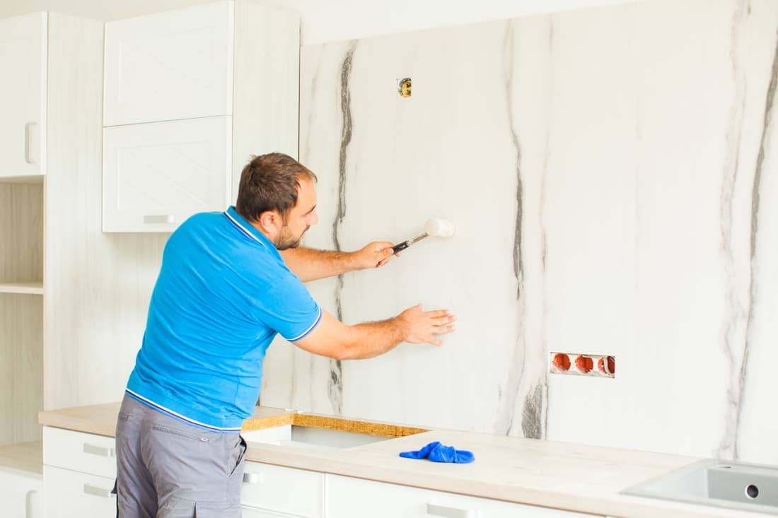 Young Man Fixing Wall Panels in the Kitchen