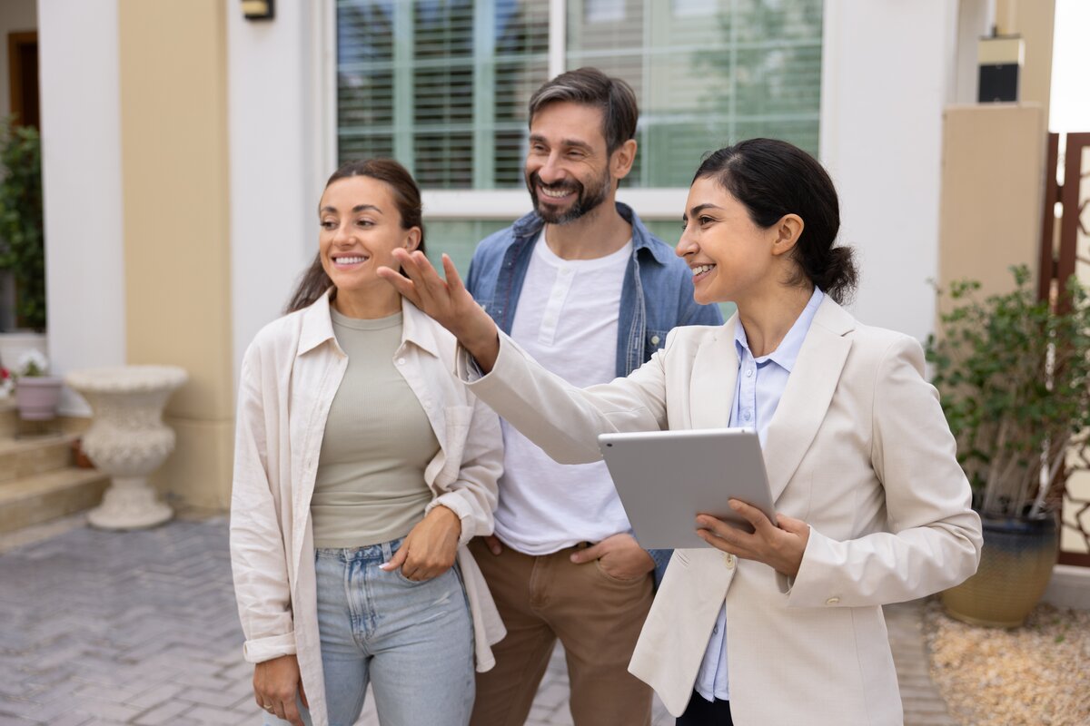 Smiling agent shows a modern home to a happy couple.