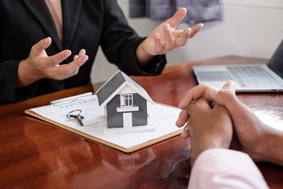 A Real Estate Agent With a Home Model is Talking to Clients About Renting a Home